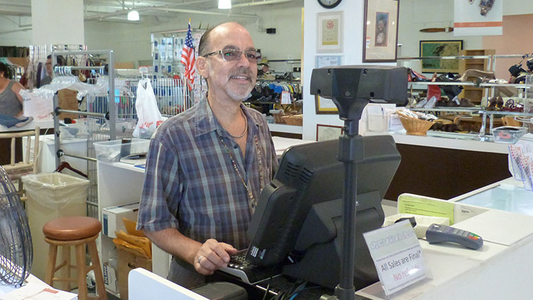 Man volunteering at cash register in Revivals store.