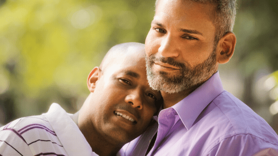 Two men embraced looking at the camera in a park